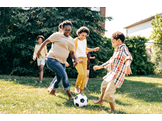 A family playing soccer in their yard